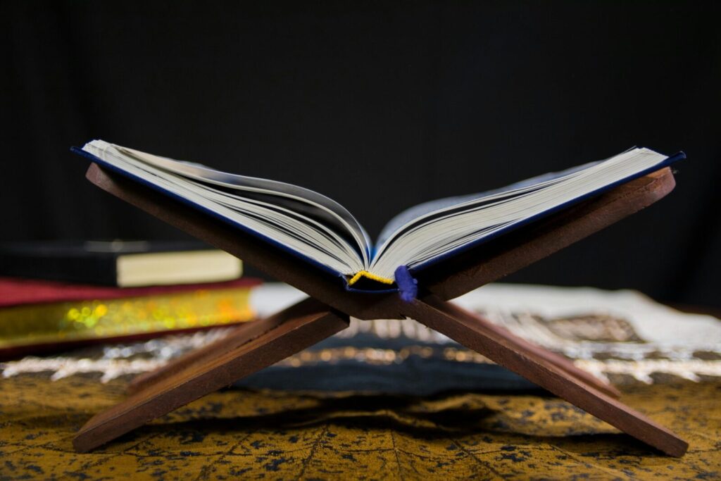 Open Quran resting on a traditional wooden stand, symbolizing faith and spirituality in Islam.